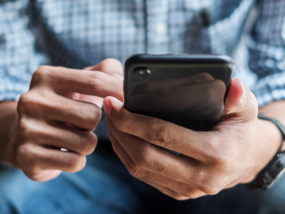 Person wearing blue plaid shirt scrolling on a black phone