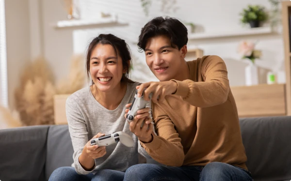 2 people playing a game while sitting on a couch