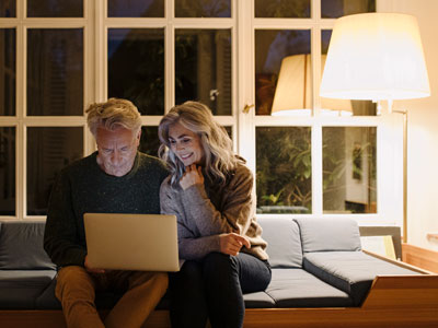 Couple sitting on a couch looking at a laptop