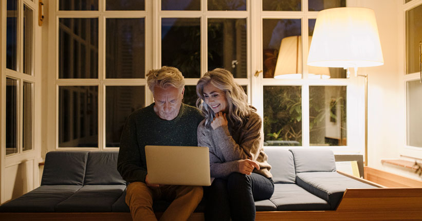 Couple sitting on a couch looking at a laptop