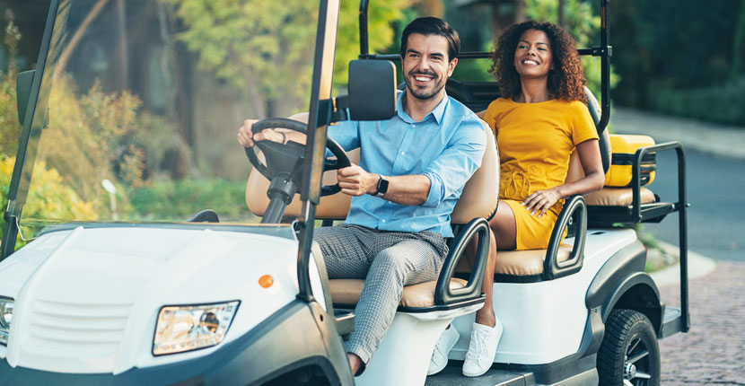 2 people in a golf cart on a path