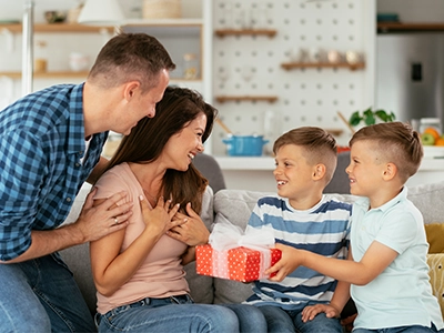 Mother receiving a gift from her kids with her partner behind her