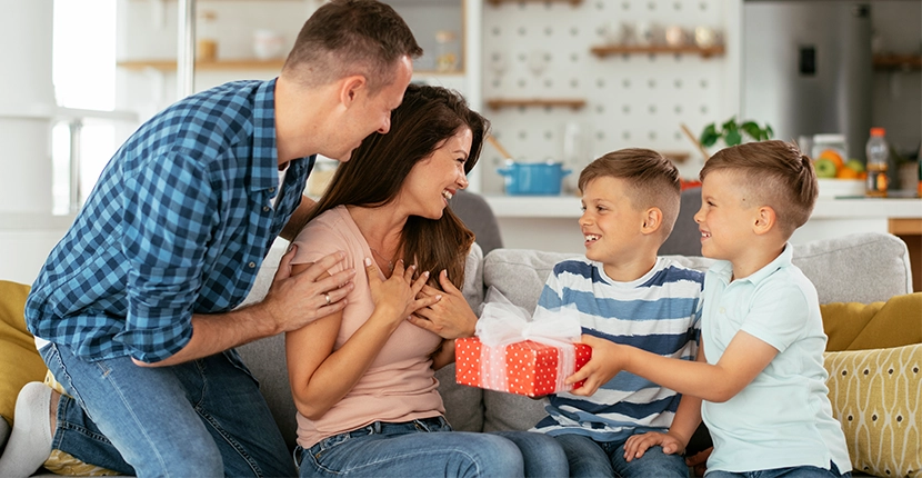 Mother receiving a gift from her kids with her partner behind her