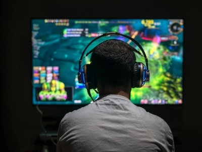 Someone with headphones on playing a game on a screen