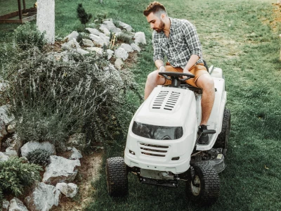 Riding a white riding lawn mower near landscaping
