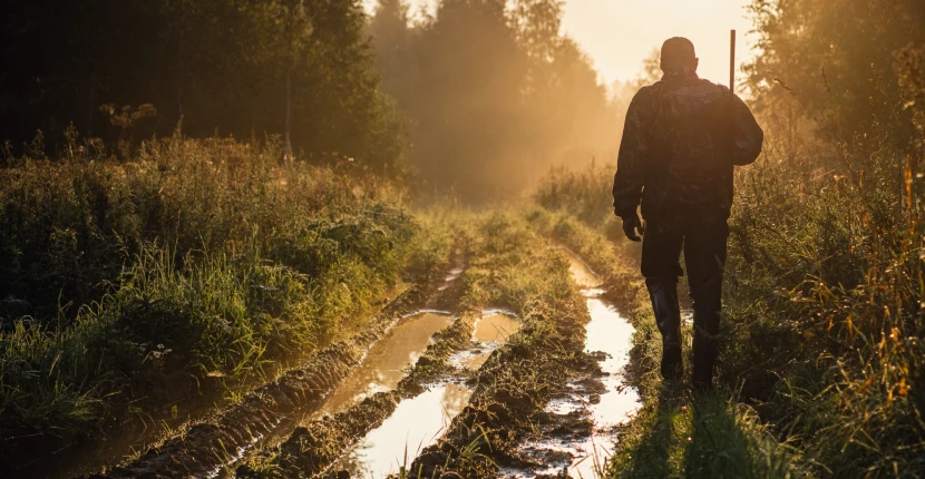 A hunter walking down a muddy path