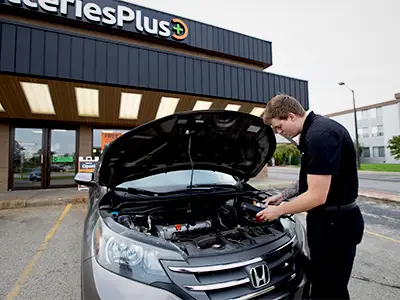 Worker checking a battery in a vehicle