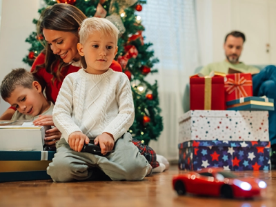 Child playing with a remote controlled vehicle with family in the background