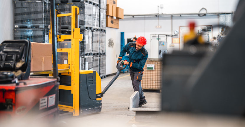 Distribution center employee pushing a motorized pallet jack