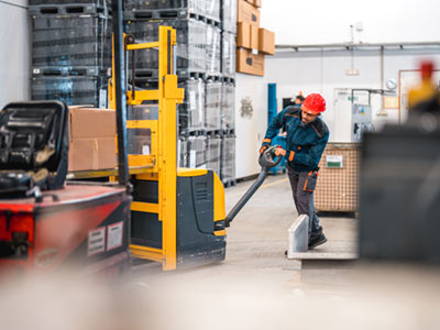 Distribution center employee pushing a motorized pallet jack