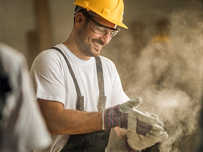 Construction worker dusting off his gloves
